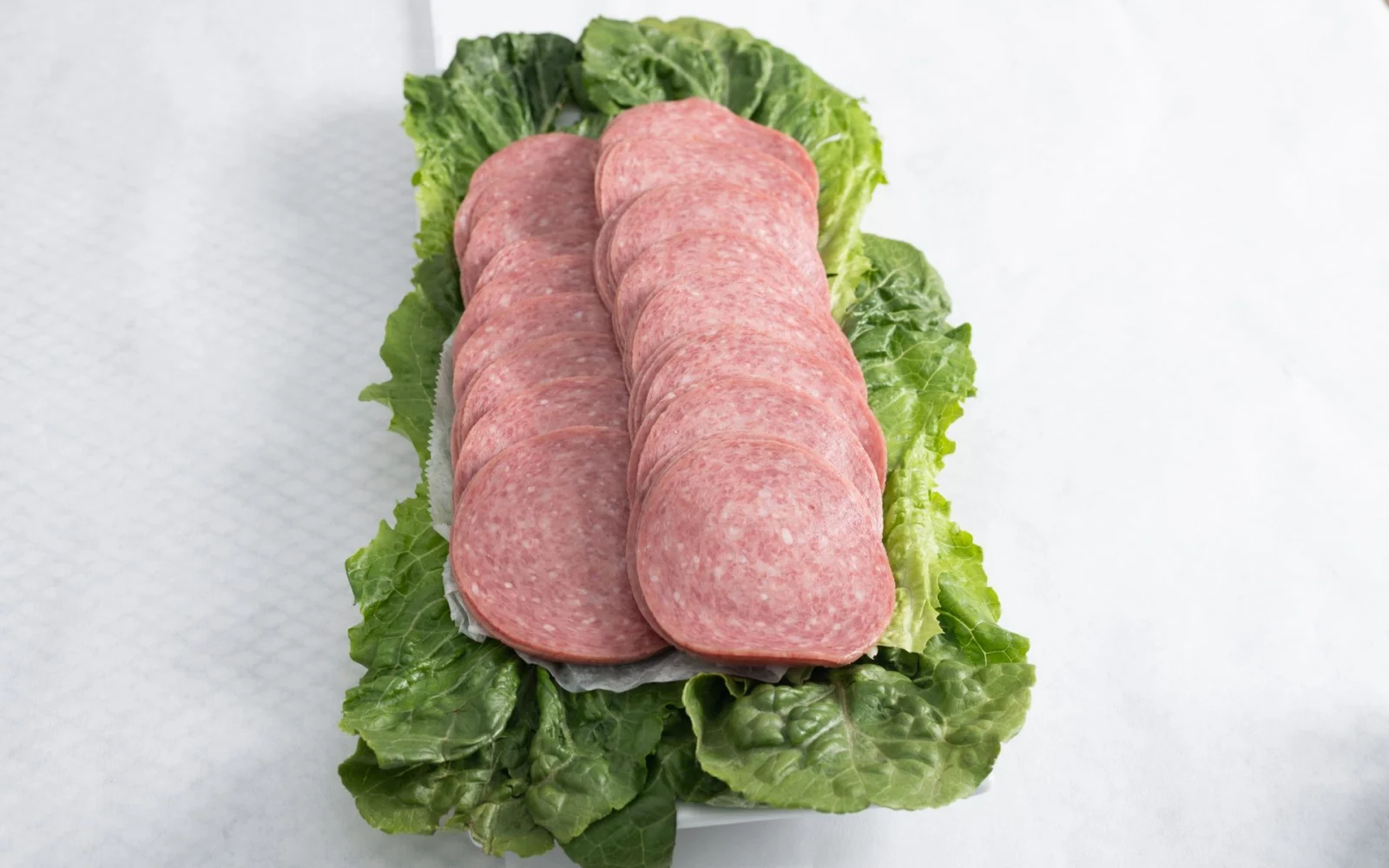 Sliced salami on a bed of romaine