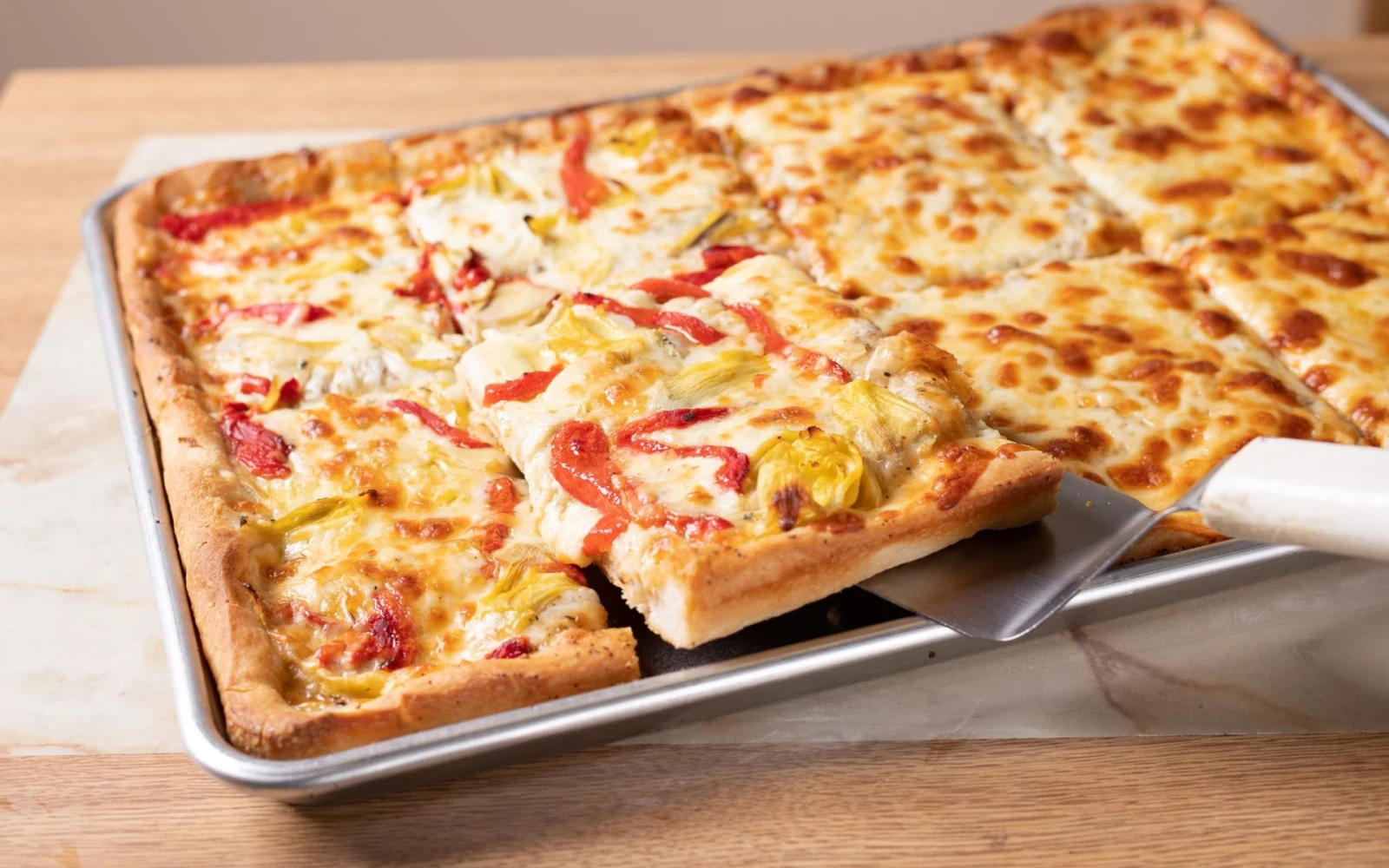 Sheet pizza with artichoke hearts and roasted red peppers